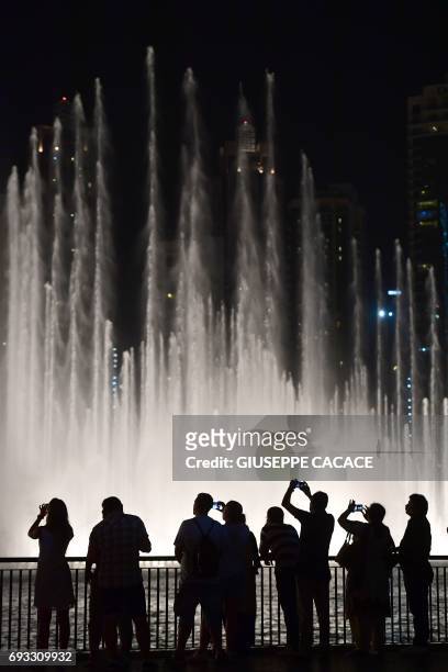 People watch the water jets of the dancing fountains in downtown Dubai, on June 6, 2017. / AFP PHOTO / GIUSEPPE CACACE