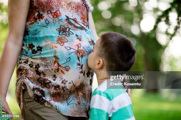 zachte peuter kissing nieuwe baby to come - belly kissing stockfoto's en -beelden