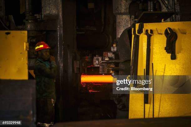 Worker looks on as a red hot steel beam is processed inside the ArcelorMittal HighVeld Steel & Vanadium Corp. Plant in eMalahleni, South Africa, on...