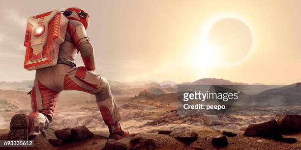 astronaut on mars kneeling and watching eclipse at sunset - space man on mars imagens e fotografias de stock