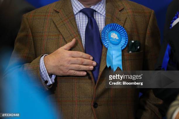 An attendee wears a rosette supporting the Conservative Party as he listens to Theresa May, U.K. Prime minister and leader of the Conservative Party,...