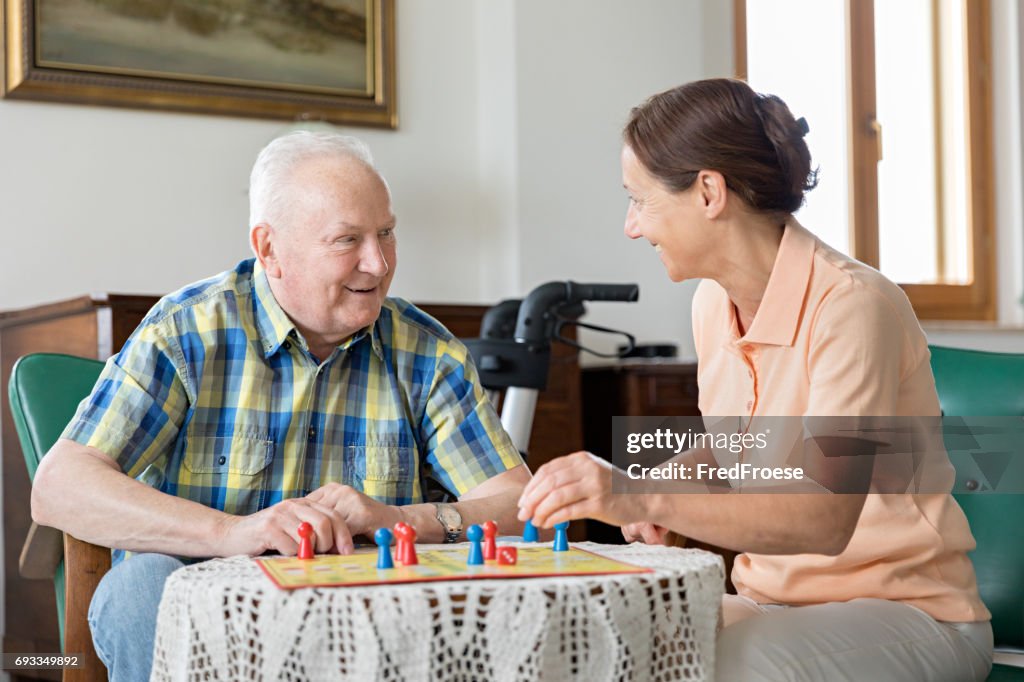 Senior woman and home caregiver playing board game