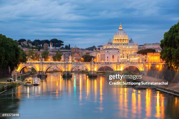 sunset view of st. peters basilica in the vatican and the ponte sant'angelo, bridge of angels, at the castel sant'angelo and river tiber in rome, italy - rom stock-fotos und bilder