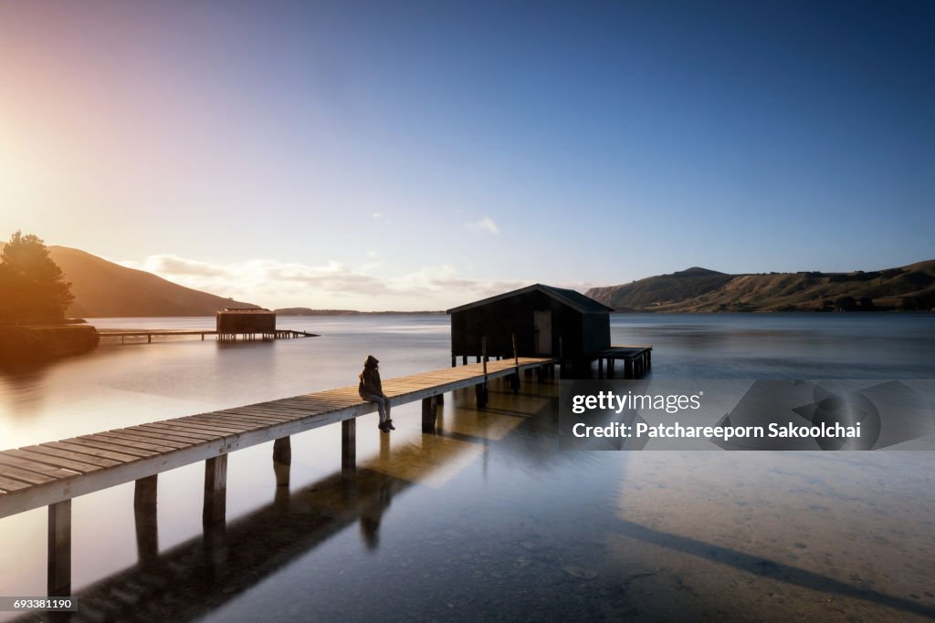 Woman in silhouette sitting at the house over the water