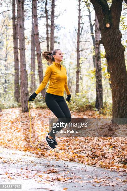 fit jonge vrouw met springtouw in een park - touwtje springen stockfoto's en -beelden