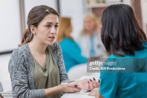 betrokken vrouw praat met triage verpleegkundige over schade - symptom stockfoto's en -beelden