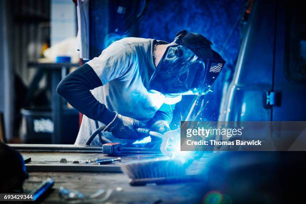 man welding metal frame in metal workshop - blue glove foto e immagini stock