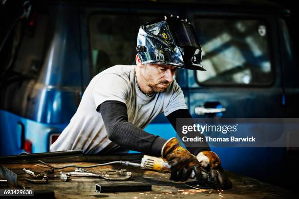 man using grinder during welding project in metal workshop - welding mask stock pictures, royalty-free photos & images