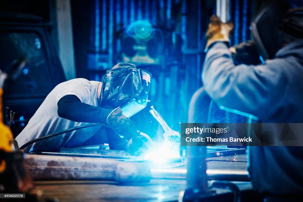 Welder welding frame in metal shop