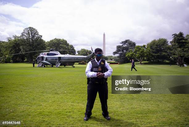 Secret service officer stands guard as U.S. President Donald Trump, left, walks towards Marine One to depart for Cincinnati on the South Lawn of the...