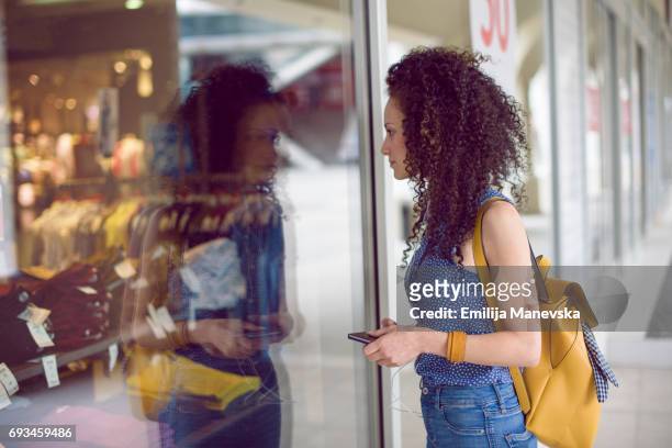 a woman looking excited through a store window - store window stock pictures, royalty-free photos & images