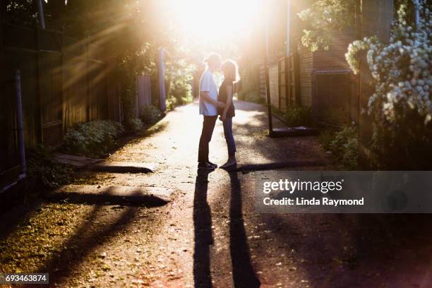 un jeune couple baiser dans une ruelle au coucher du soleil - tomber amoureux photos et images de collection