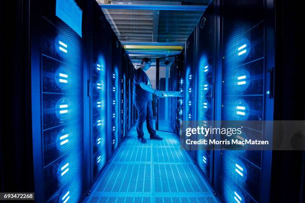 An employee of the German Climate Computing Center poses next to the "Mistral" supercomputer, installed in 2016, at the German Climate Computing...