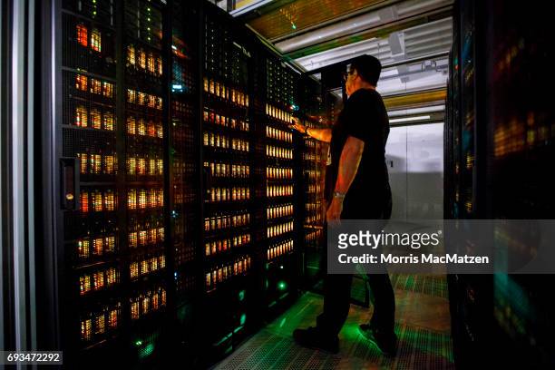An employee of the German Climate Computing Center poses next to the "Mistral" supercomputer, installed in 2016, at the German Climate Computing...