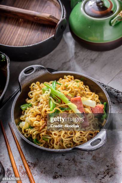 yakisoba, japanse pan gebakken noedels, met ham en lente-ui in gietijzer pot - rookkaas stockfoto's en -beelden