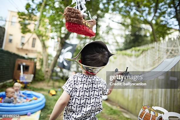 boy hits a pinata in backyard. - pinata sword stockfoto's en -beelden