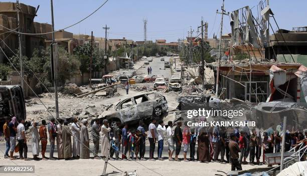 Iraqis stand in line to receive food aid in western Mosul's Zanjili neighbourhood on June 7 during ongoing battles as Iraqi forces try to retake the...