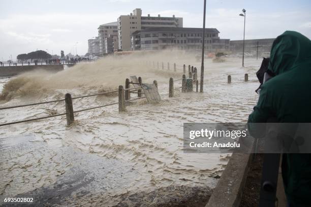 People are seen over the bridge as the huge waves hit coastline during the heavy storm in Cape Town, South Africa on June 7, 2017.