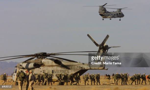 United States Marines march in front of Marine helicopters on the American military compound at Kandahar Airport January 21, 2002 in Kandahar,...