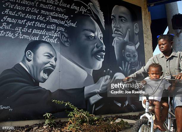 Children ride a bicycle past a mural in honor of the slain civil rights leader Martin Luther King Jr. January 21, 2002 in Miami, Florida.