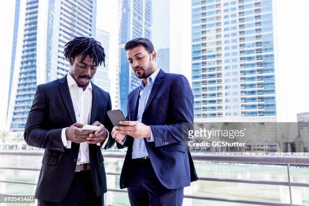 colleagues discussing a business proposal using a smart phone - bahrain business stock pictures, royalty-free photos & images