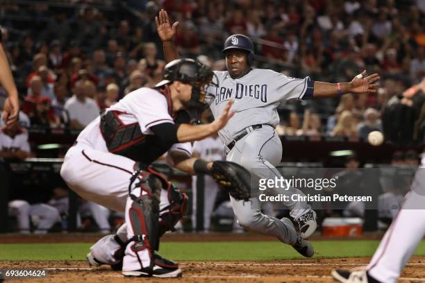 Jose Pirela of the San Diego Padres safely slides into home plate to score a run past catcher Jeff Mathis of the Arizona Diamondbacks during the...