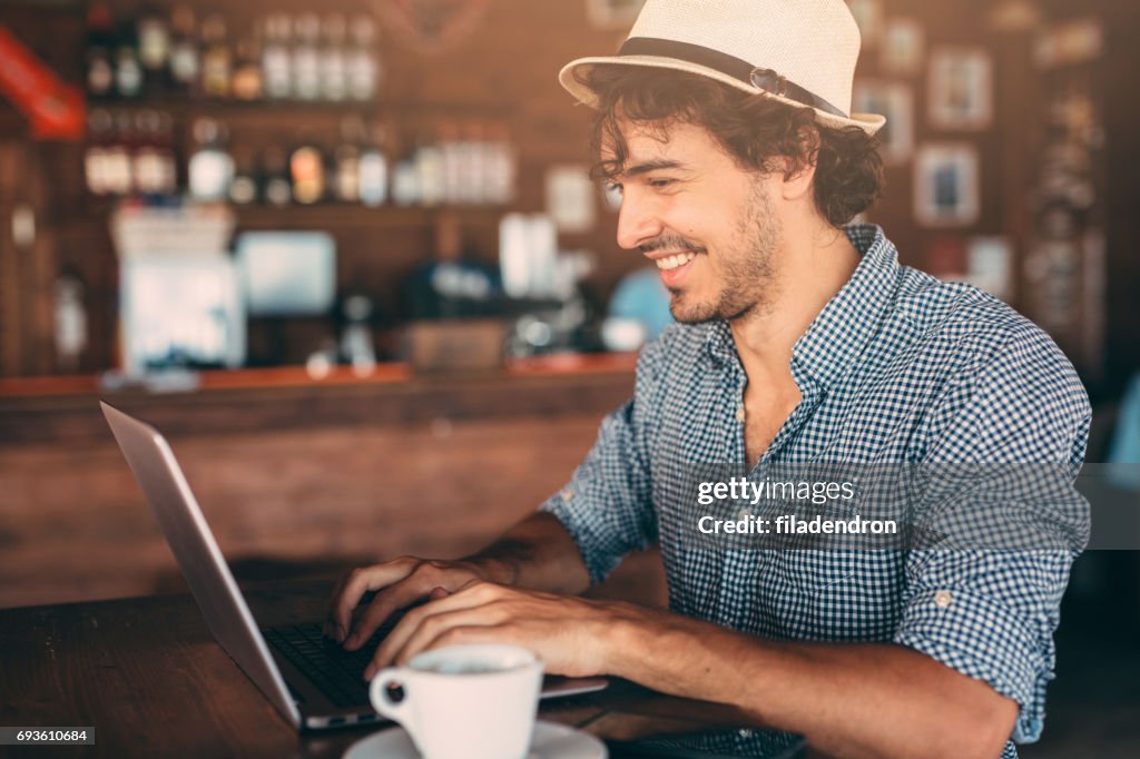 Attractive man using a laptop at the cafe