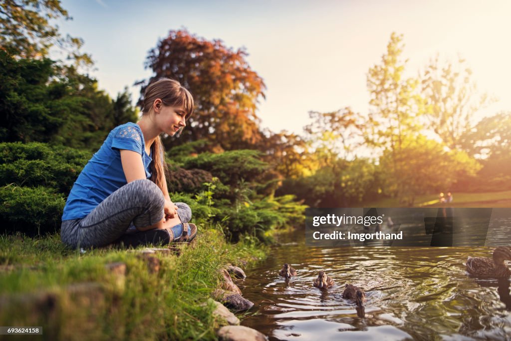 Girl observing ducks swimming in the city park