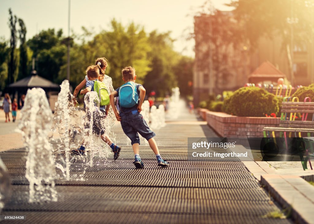 Kids running between fountains on a hot summer day.