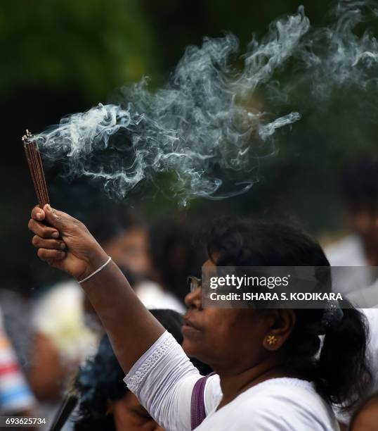 Sri Lankan Buddhist devotee holds incense at the Kelaniya Temple during the Poson festival in the Colombo suburb of Kelaniya on June 8, 2017. Sri...