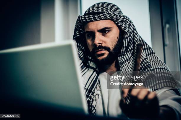 young arabian man looking at laptop in office - serbia tradition stock pictures, royalty-free photos & images