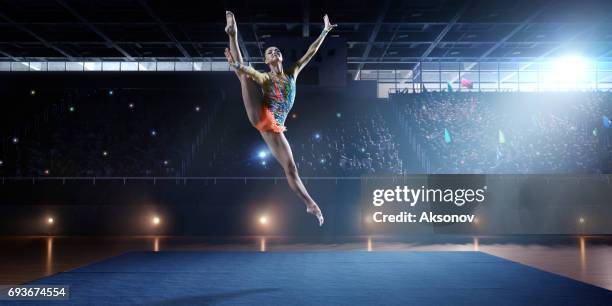 une fille gymnaste fait un saut sur une grande scène professionnelle - gymnaste photos et images de collection