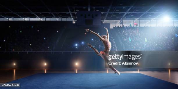 a gymnast girl makes a leap on a large professional stage - acrobat performer stock pictures, royalty-free photos & images