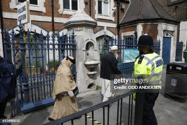 People walk past a police officer outside a polling station on Brick Lane, east London on June 8 as Britain holds a general election. As polling...