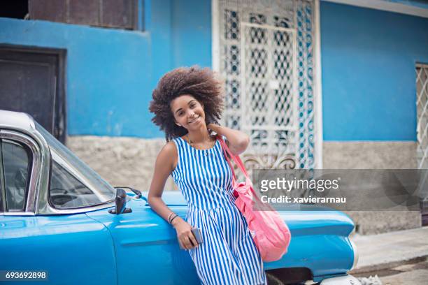 Young woman leaning on blue taxi in city