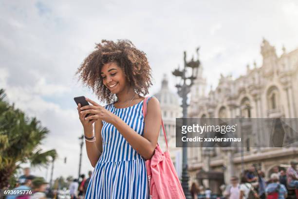 woman texting on smart phone in city - blue purse stock pictures, royalty-free photos & images
