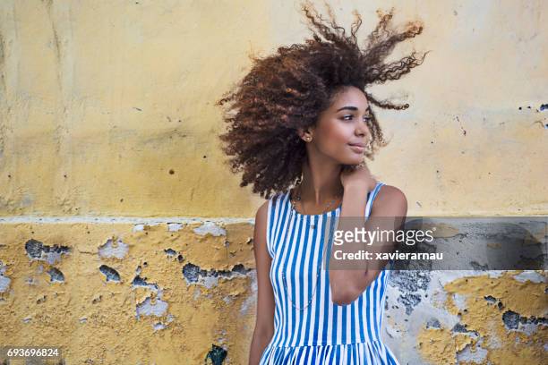 Woman curly hair looking away over weathered wall