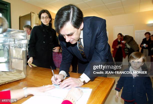 Le ministre des Affaires sociales François Fillon, tête de liste aux élections régionales dans les Pays de Loire signe le registre sous les yeux...