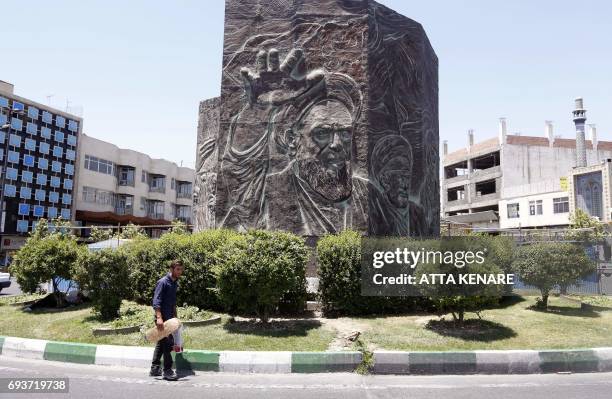 Iranians walks past a sculpture bearing an imagine of late Ayatollah Ruhollah Khomeini in Enqelab Square Tehran on June 8, 2017 one day after twin...