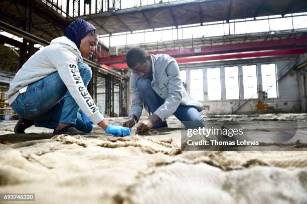 The artist Ibrahim Mahama of Ghana works on jute bags for his next artwork at Henschel Hall on June 8, 2017 in Kassel, Germany. The documenta 14 is...