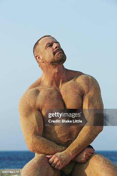 muscle man on beach  kneeling w sand - hunky guy on beach stock pictures, royalty-free photos & images