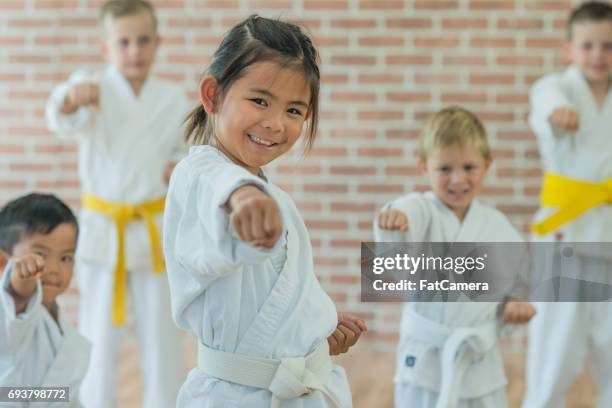 little girl throws a punch at martial arts practice - karate stock pictures, royalty-free photos & images