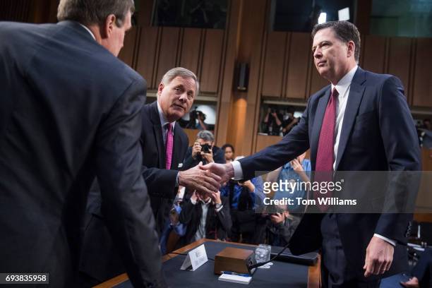 Former FBI Director James Comey, right, is greeted by Chairman Richard Burr, R-N.C., center, and Vice-Chair Mark Warner, D-Va., before testifying...