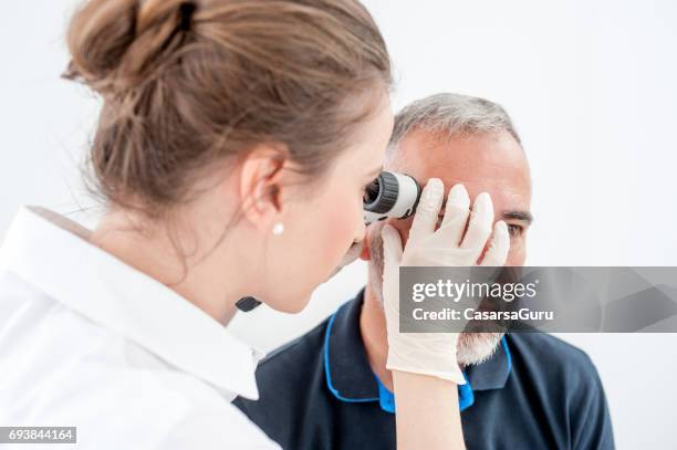 dermatologist inspecting skin moles on patient face - loupe imagens e fotografias de stock