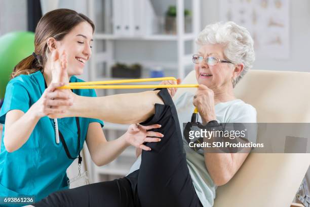 physical therapist helps patient use resistance band - human knee stock pictures, royalty-free photos & images