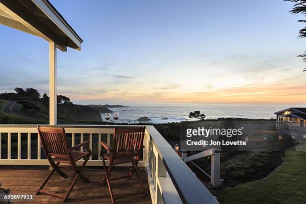 deck, chairs and  wine overlooking sea and sunset - steilküste stock-fotos und bilder