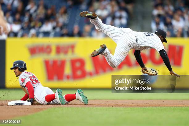 Didi Gregorius of the New York Yankees is tripped up after tagging out Mookie Betts of the Boston Red Sox trying to steal second base in the first...