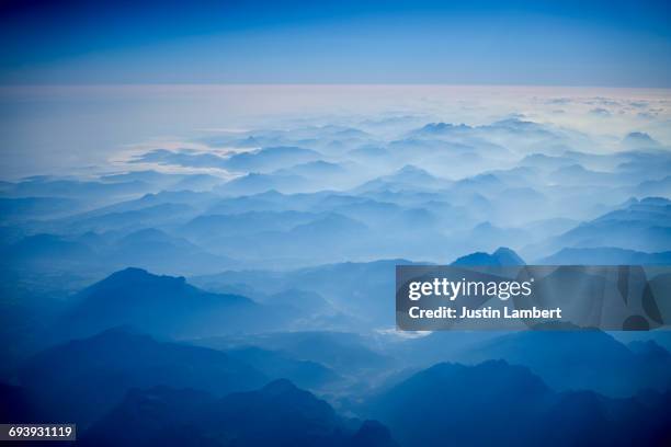 austrian alps from a plane window in morning - bright colour photos stock illustrations