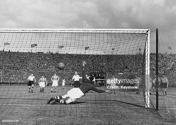 Bob Hesford, goalkeeper for Huddersfield Town dives to his right as George Mutch of Preston North End scores the only goal of the match from the...