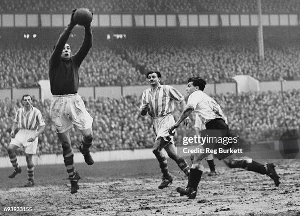 Goalkeeper Dennis Herod of Stoke City is challenged by centre forward Len Duquemin of Spurs as Stoke City centre back Frank Mountford C) looks on...